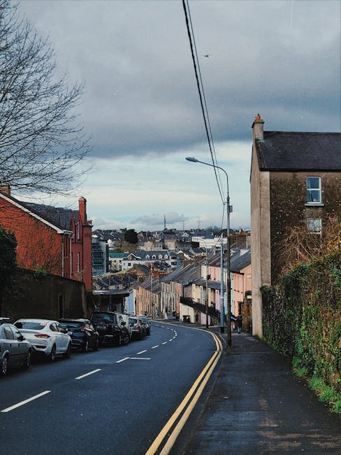 A street scene during daytime showing multiple parked vans and delivery vehicles along the curbside of Dublin Road in Longford, with some vehicles positioned near building entrances. The street has a 